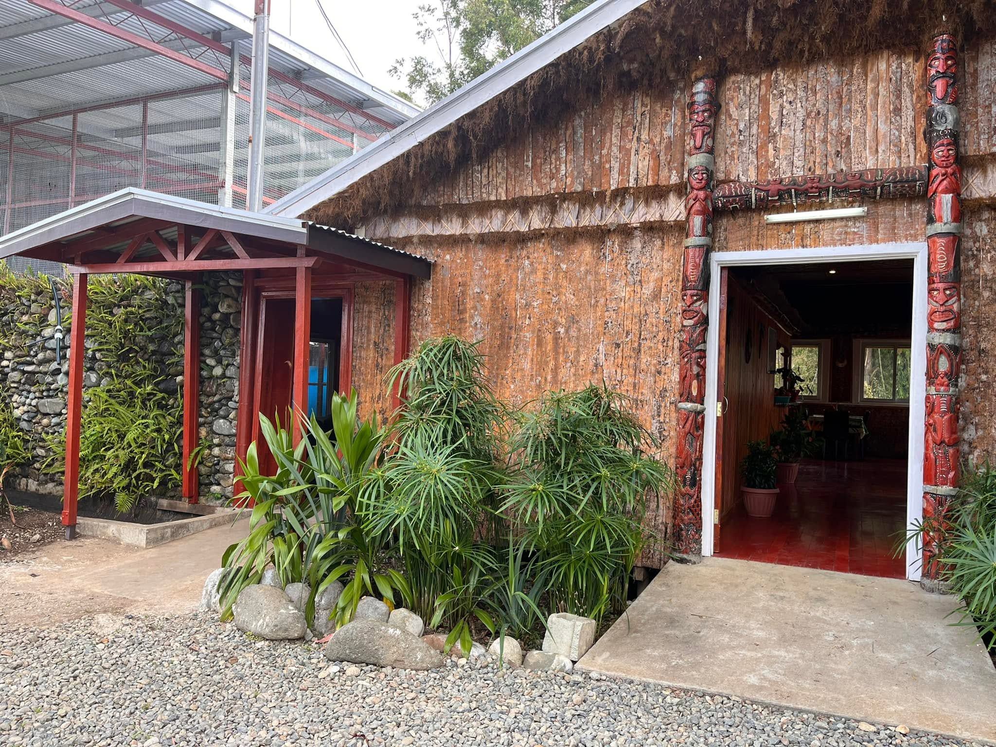 Traditional timber building with ornate carved totem poles and garden plants.