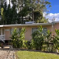 Siding-clad bungalow with solar water heater and tropical landscaping.