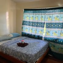 Simple bedroom setup with patterned blue curtains and made bed.