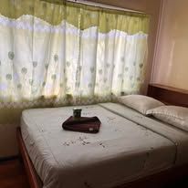 Double bed with white linens and light green patterned window curtains.