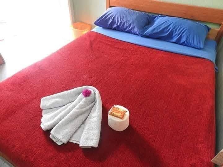 Double bed with red bedding and folded towels with local soap.