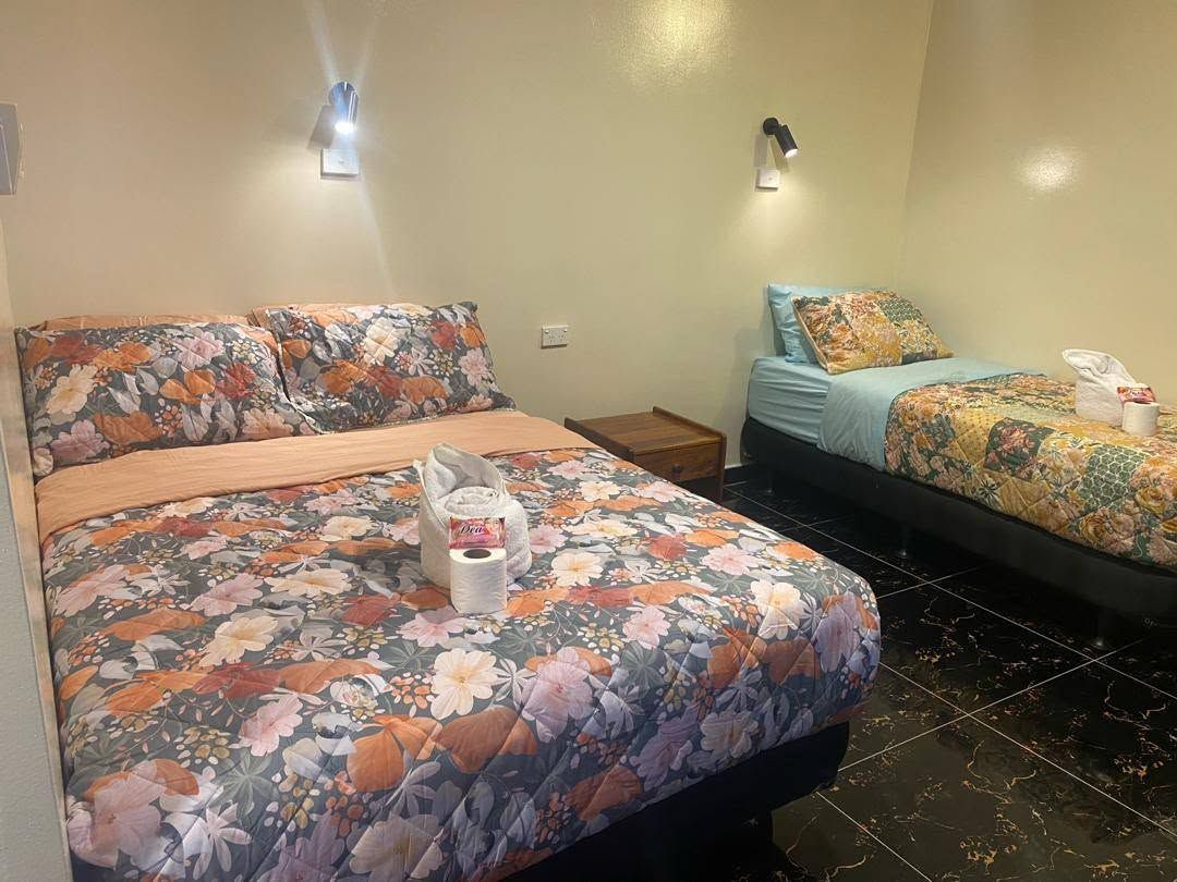 Twin room featuring floral bedspreads and dark tiled flooring.