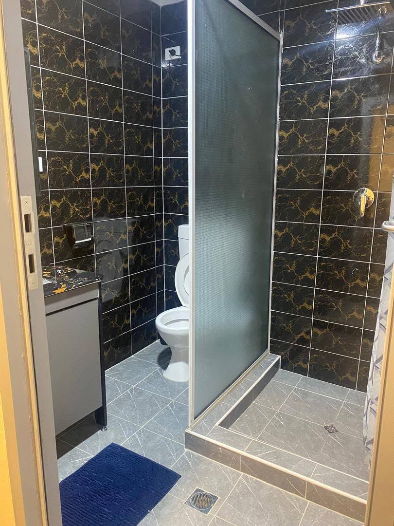 Tiled bathroom with walk-in shower and frosted glass partition.