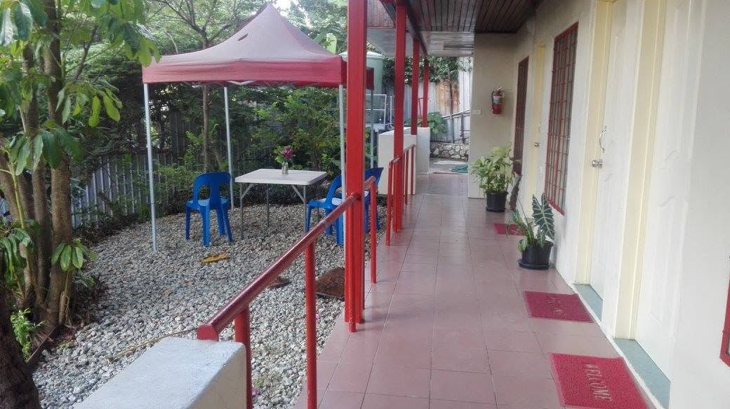 Tiled walkway with red railing and an outdoor garden seating area.