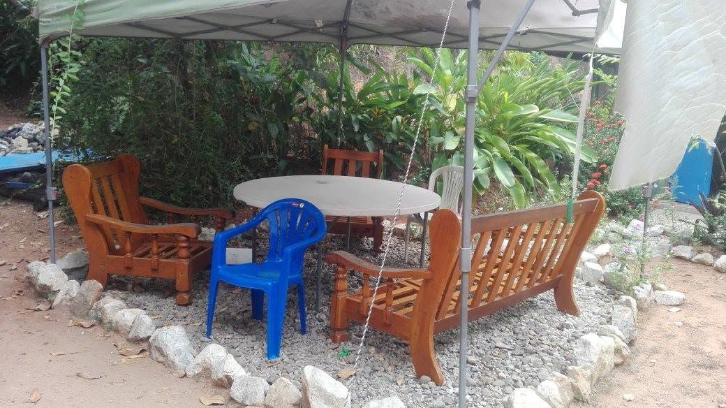 Covered outdoor seating area with wooden and plastic furniture.