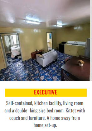 Executive suite with a blue patterned carpet, sofa, and dining area.