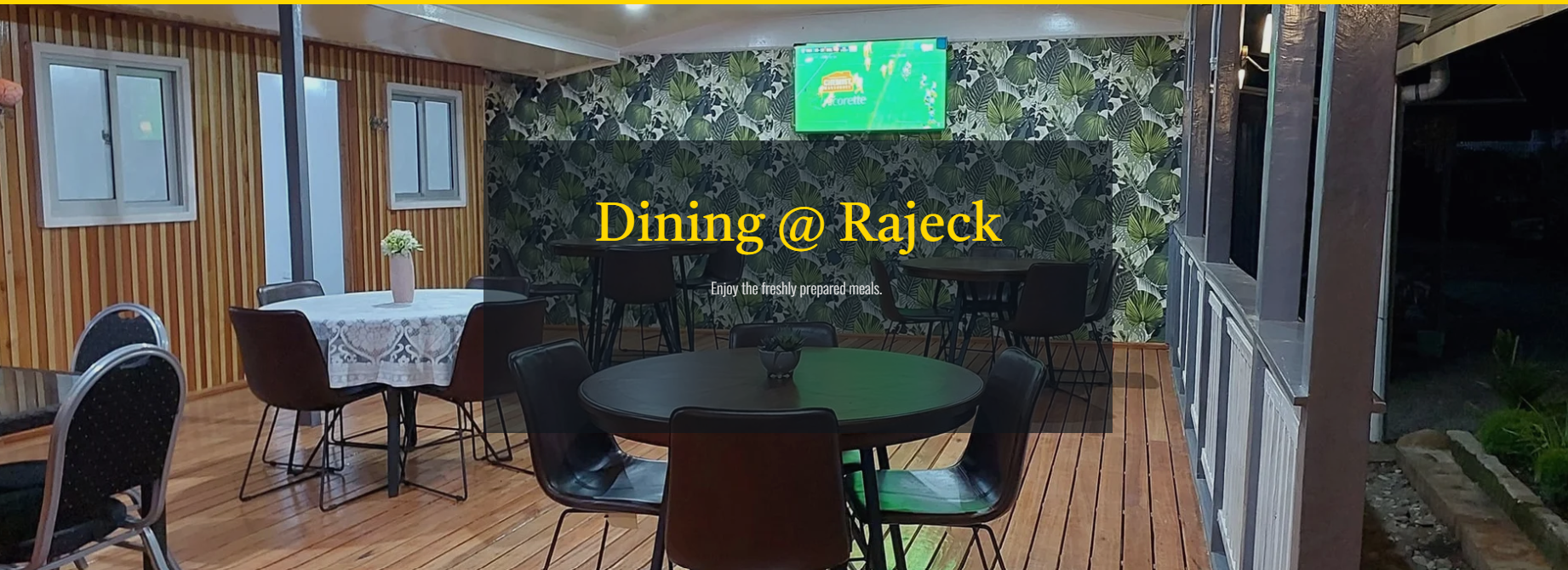 Restaurant dining area with wooden floors and decorative leaf-patterned wall.