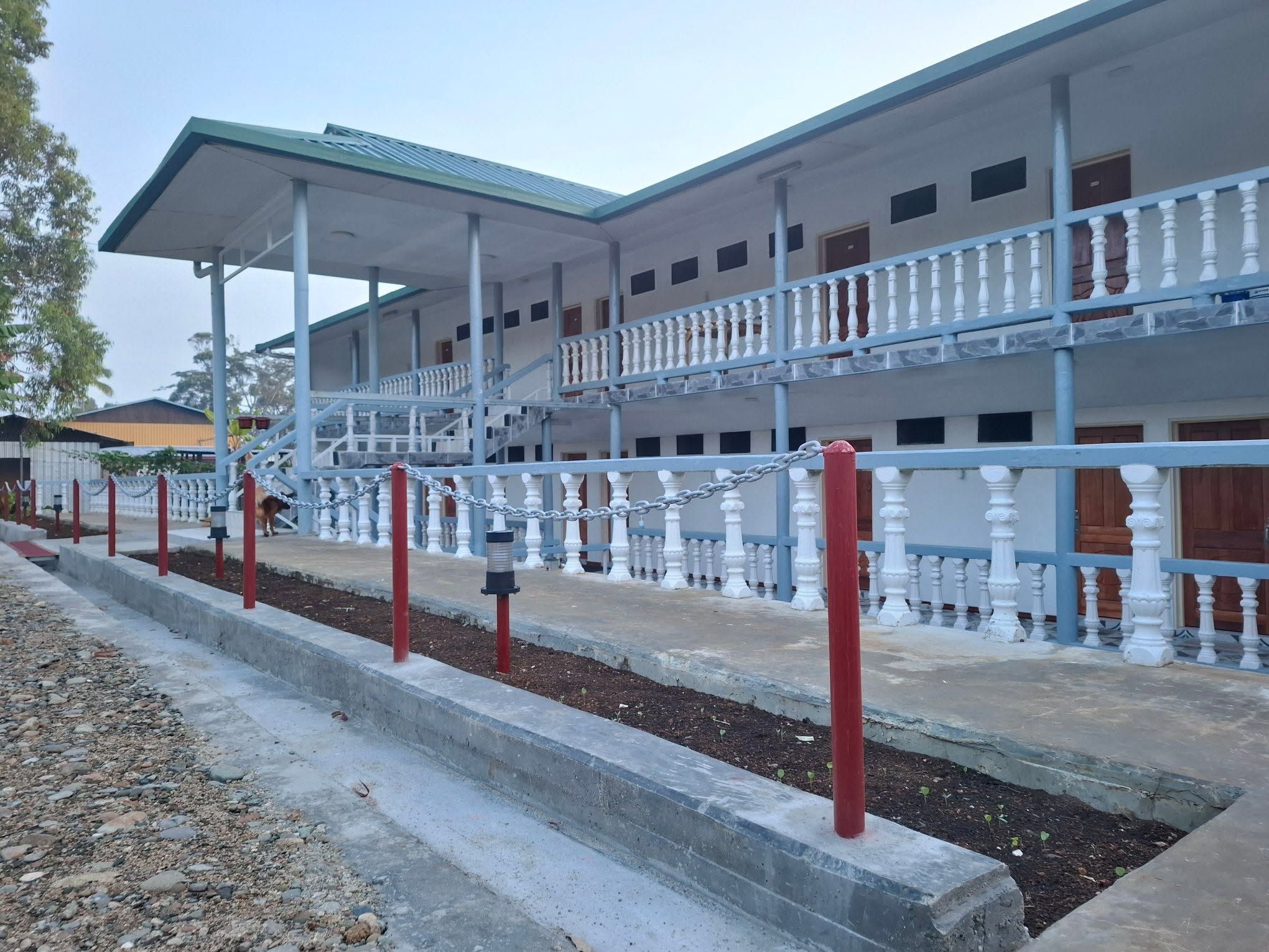 Two-story guest house exterior with white balustrades and paved walkway.