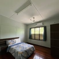 Spacious bedroom with polished wooden floors and air conditioning.