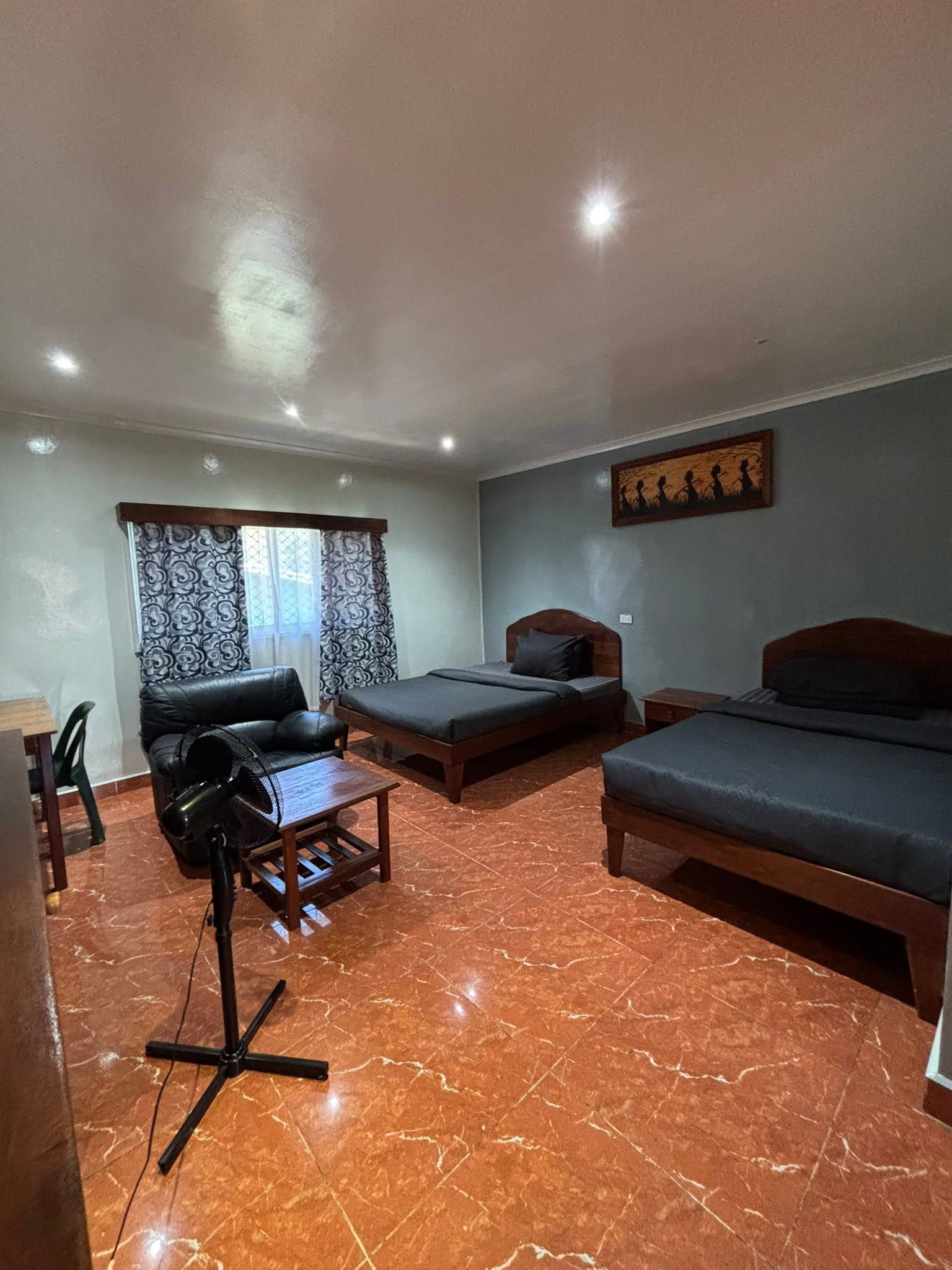 Spacious guest room featuring two beds, polished tile floors, and a seating area.