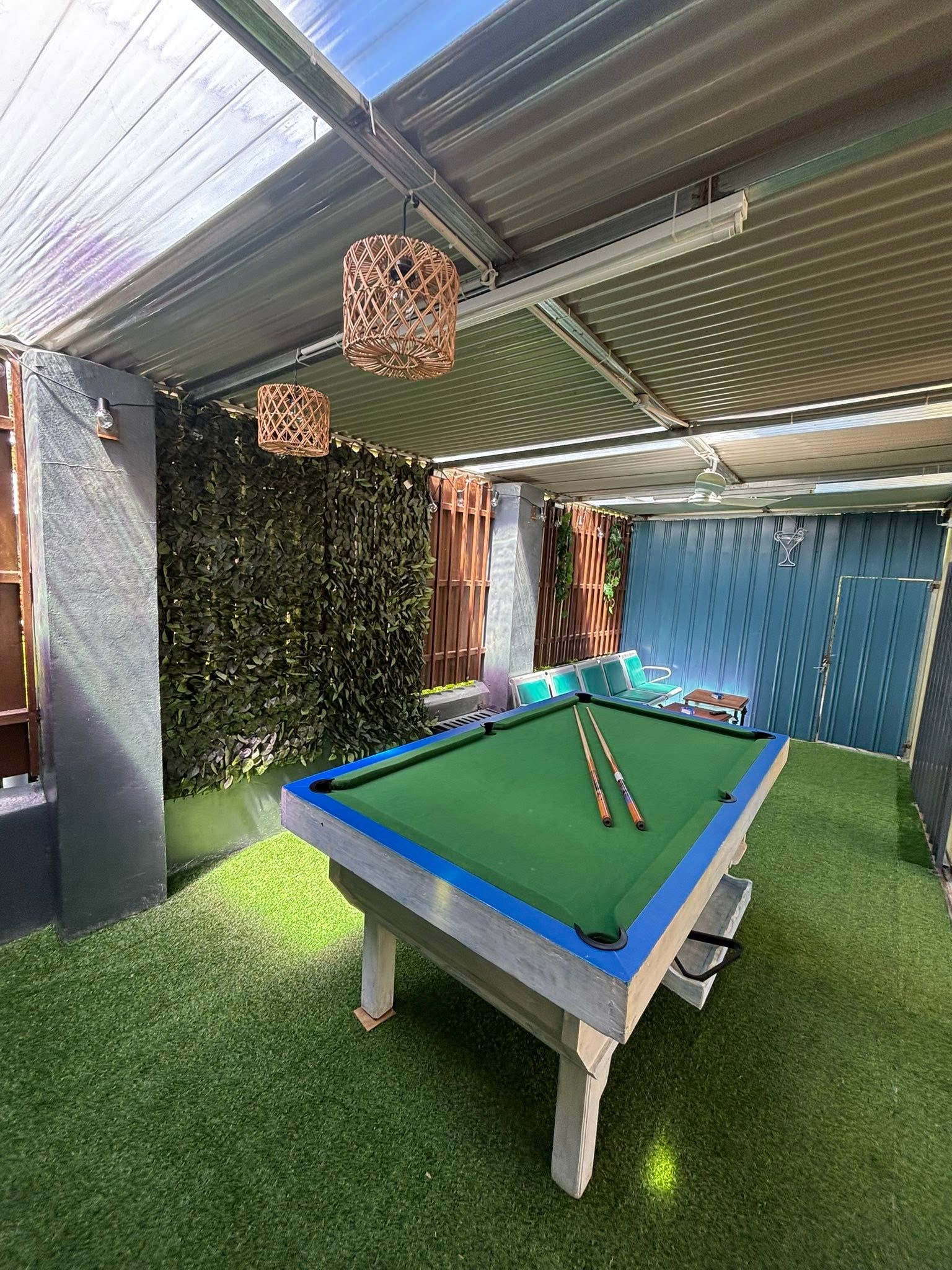 Outdoor recreation area with a pool table and artificial grass flooring.