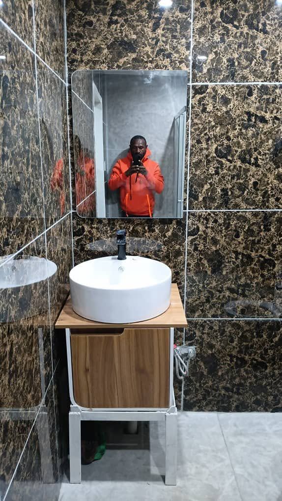 Modern bathroom vanity featuring a vessel sink and marble pattern wall tiles.