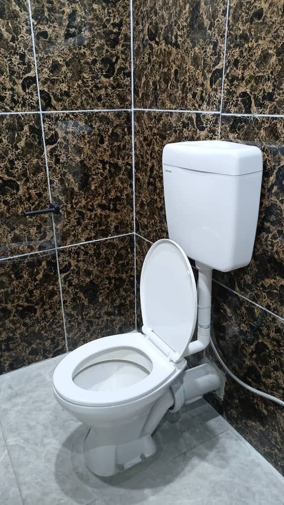 White porcelain toilet installed against dark marble-effect tiled walls.