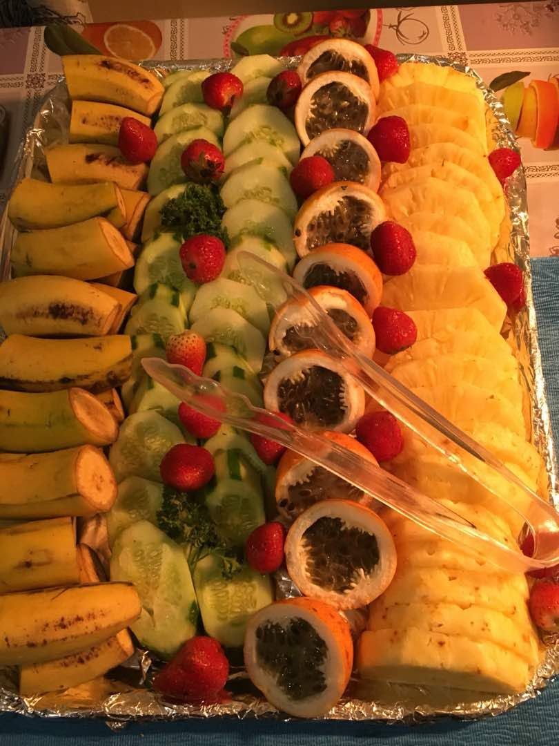 Fresh fruit platter with pineapple, passion fruit, cucumber, and strawberries.