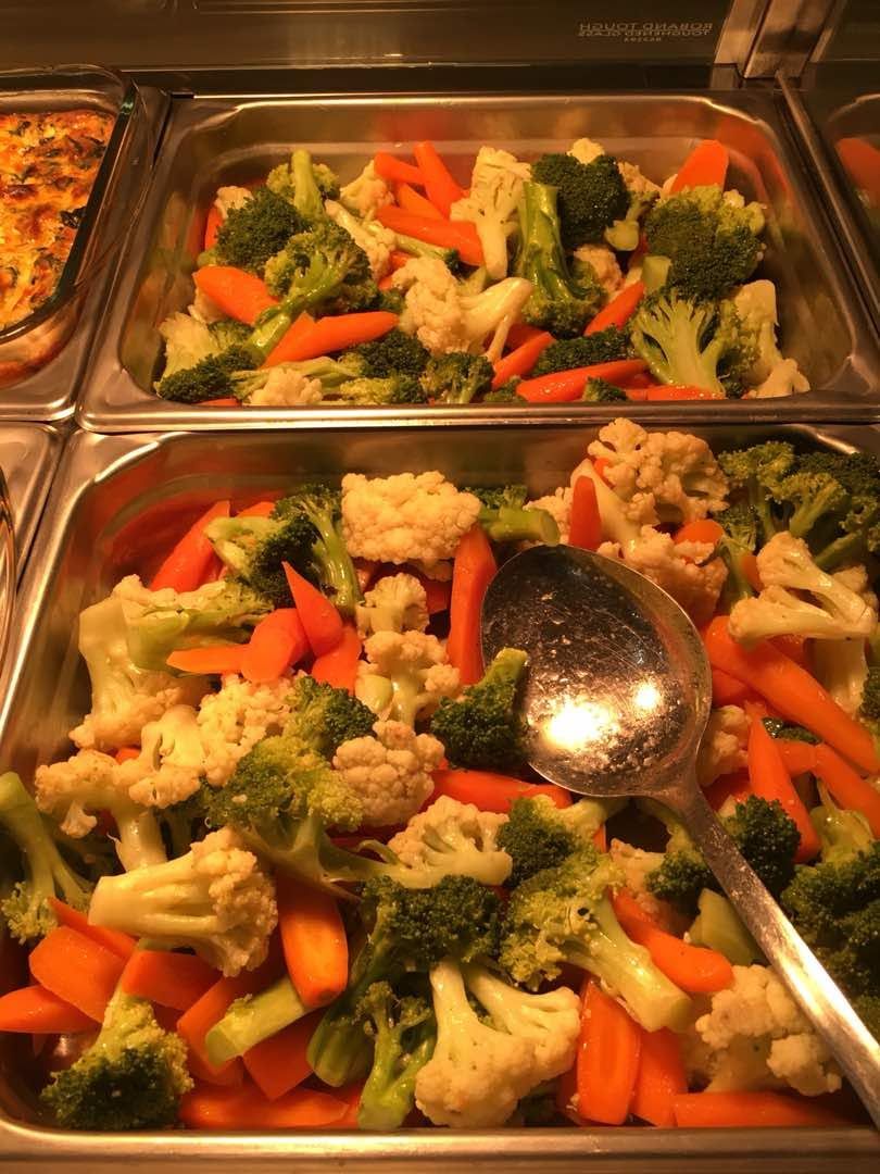 Steamed broccoli, cauliflower, and carrots served in buffet warming trays.