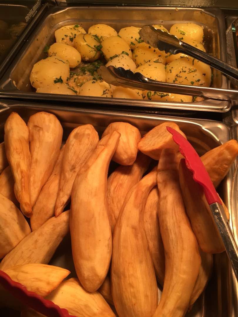 Buffet selection of roasted sweet potatoes and herb-seasoned white potatoes.