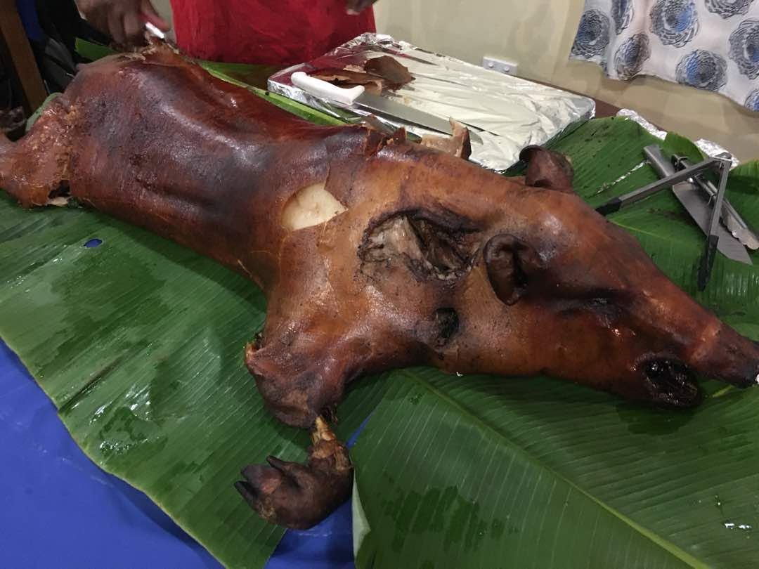 Whole roasted pig served on traditional green banana leaves.