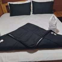 Close-up of a made bed with dark pillows and towels.