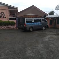 Grey shuttle van parked in front of the motel units.