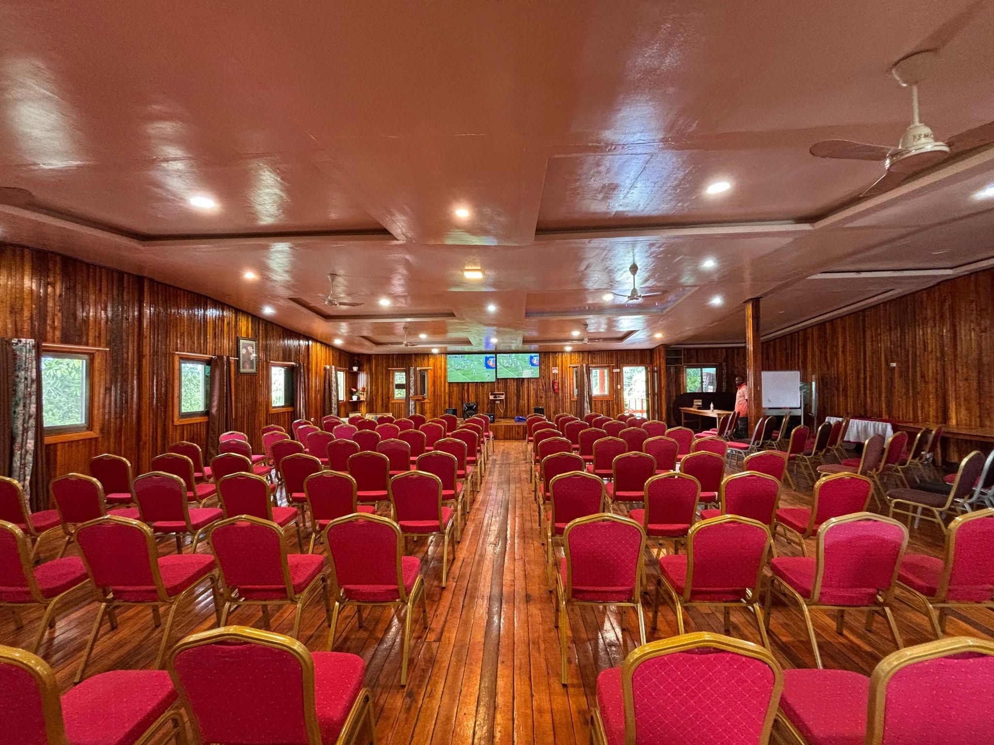 Spacious conference room with rows of red chairs.