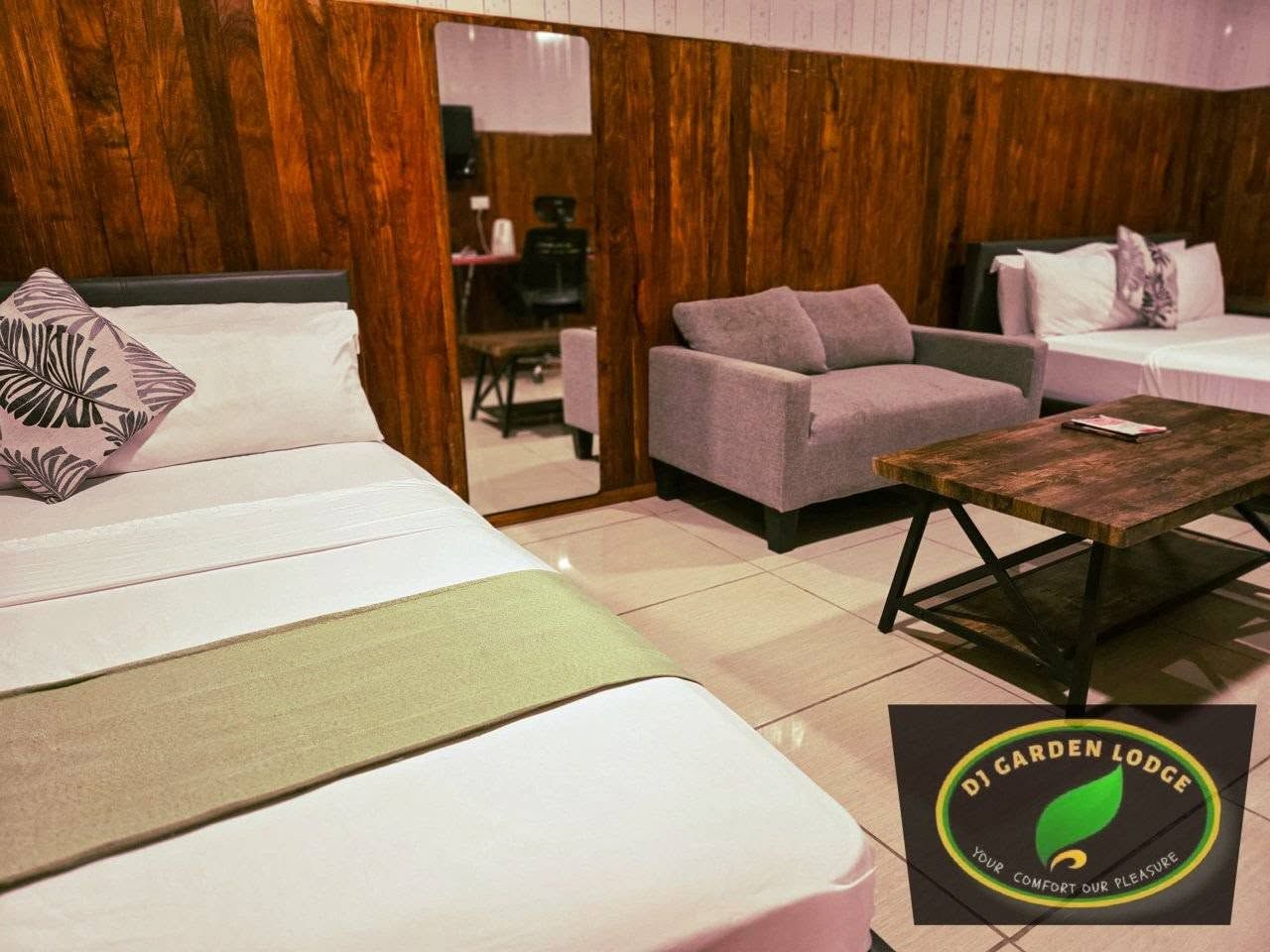 Hotel room with wood paneled walls, gray sofa, and coffee table