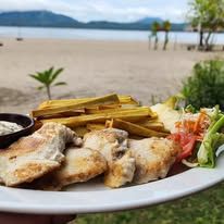 A plate of grilled fish and fried plantains served overlooking the beach.