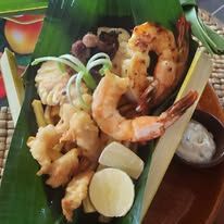 A serving of grilled prawns and fried seafood presented on a banana leaf.