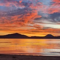 Vibrant sunset over the sea with mountains visible on the horizon.