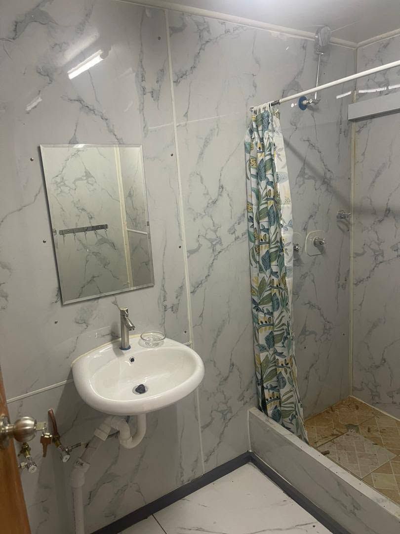 Bathroom ensuite with marble-effect wall panels, sink, and shower curtain.