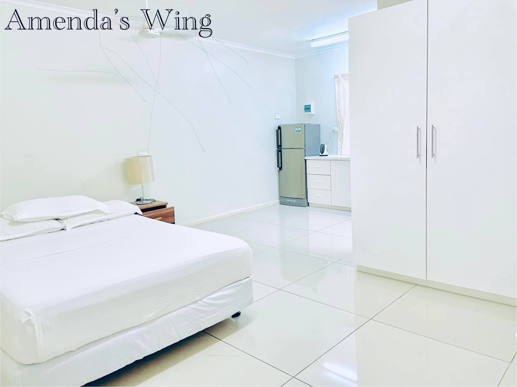 Guest suite with large bed, white wardrobe, and full-sized refrigerator.