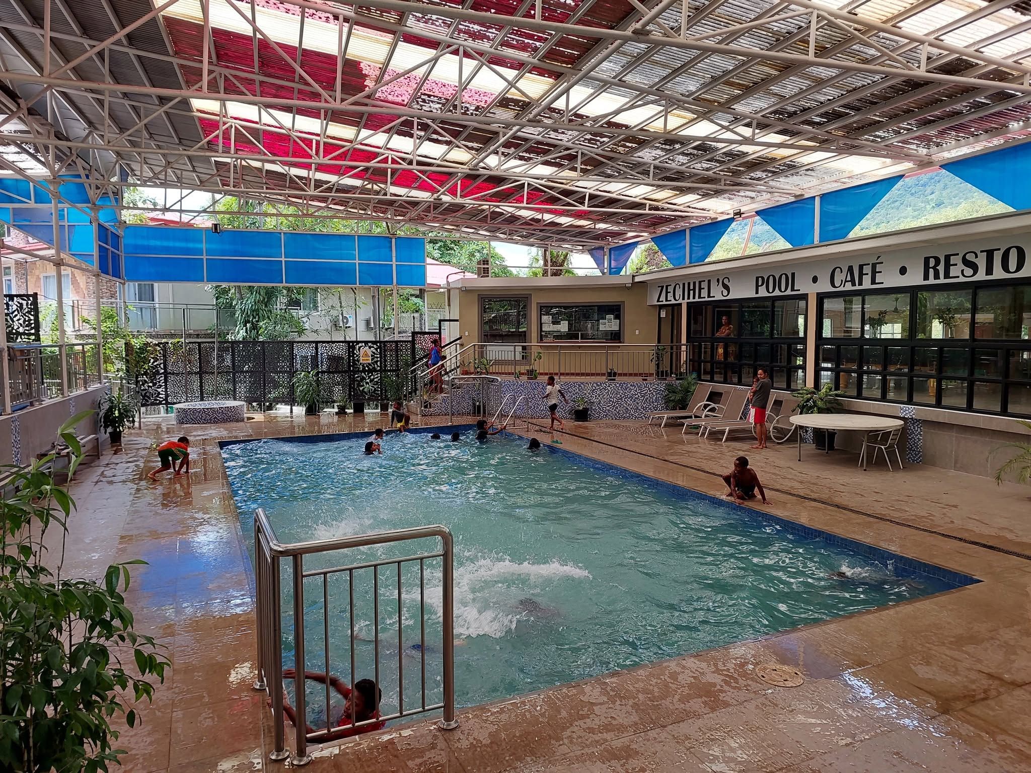 Undercover swimming pool area with adjacent cafe and lounge seating.