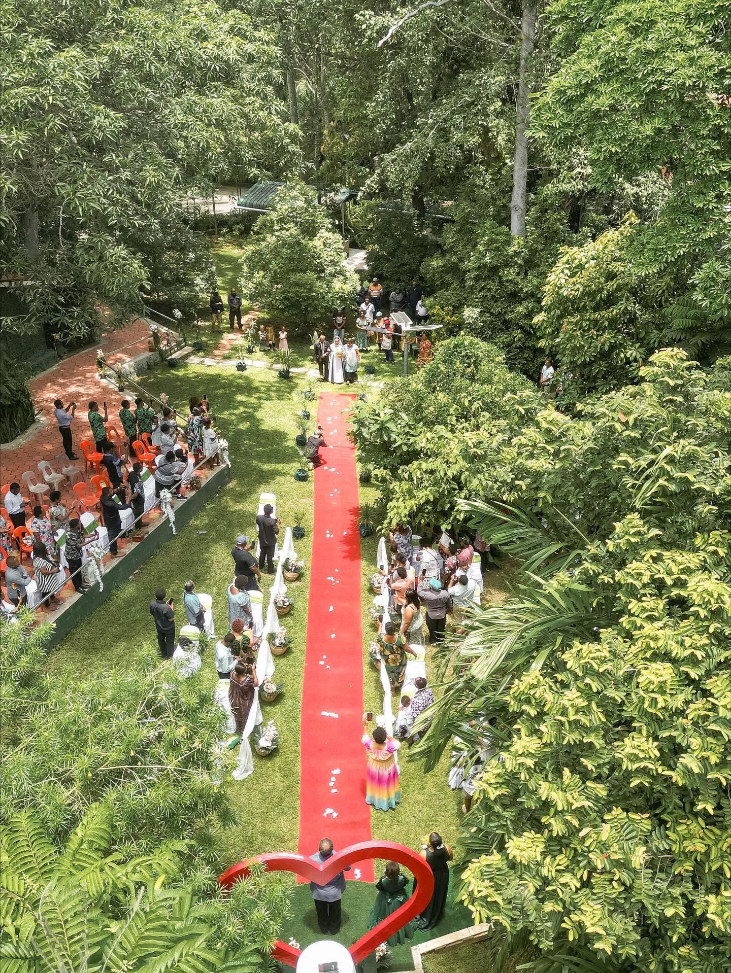 Outdoor lawn area configured for a wedding ceremony with red carpet and seating.