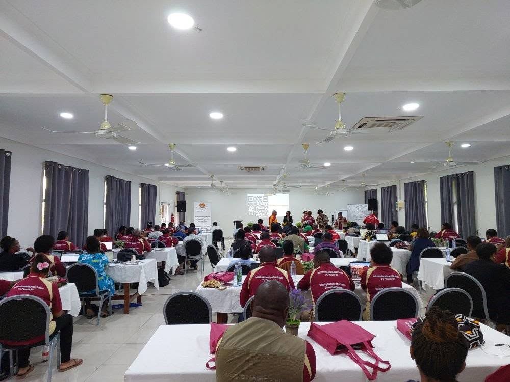 Indoor conference hall with rows of tables and chairs arranged for a workshop.