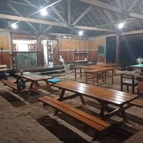 Spacious open-air dining hall with several large wooden picnic-style tables.