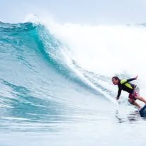 Close-up action shot of a surfer balancing on a clear crested wave.