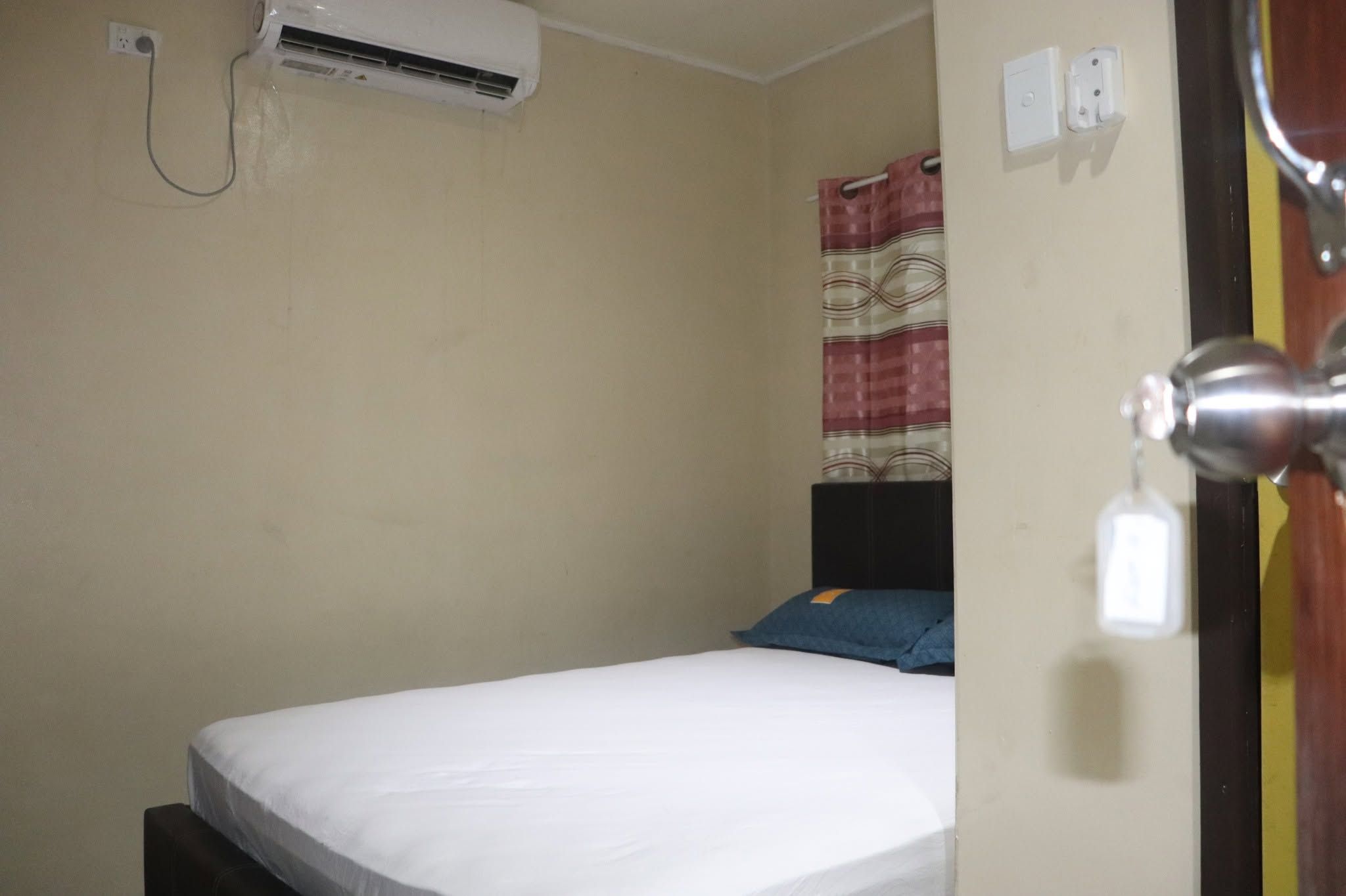 Bedroom interior with air conditioning unit and white bed linens.