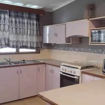 Fully equipped guest kitchen with stove, oven, sink, and cabinetry.