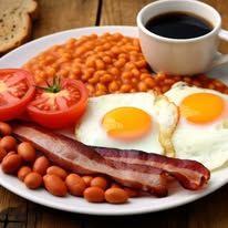 Plated cooked breakfast featuring eggs, bacon, beans, and coffee.