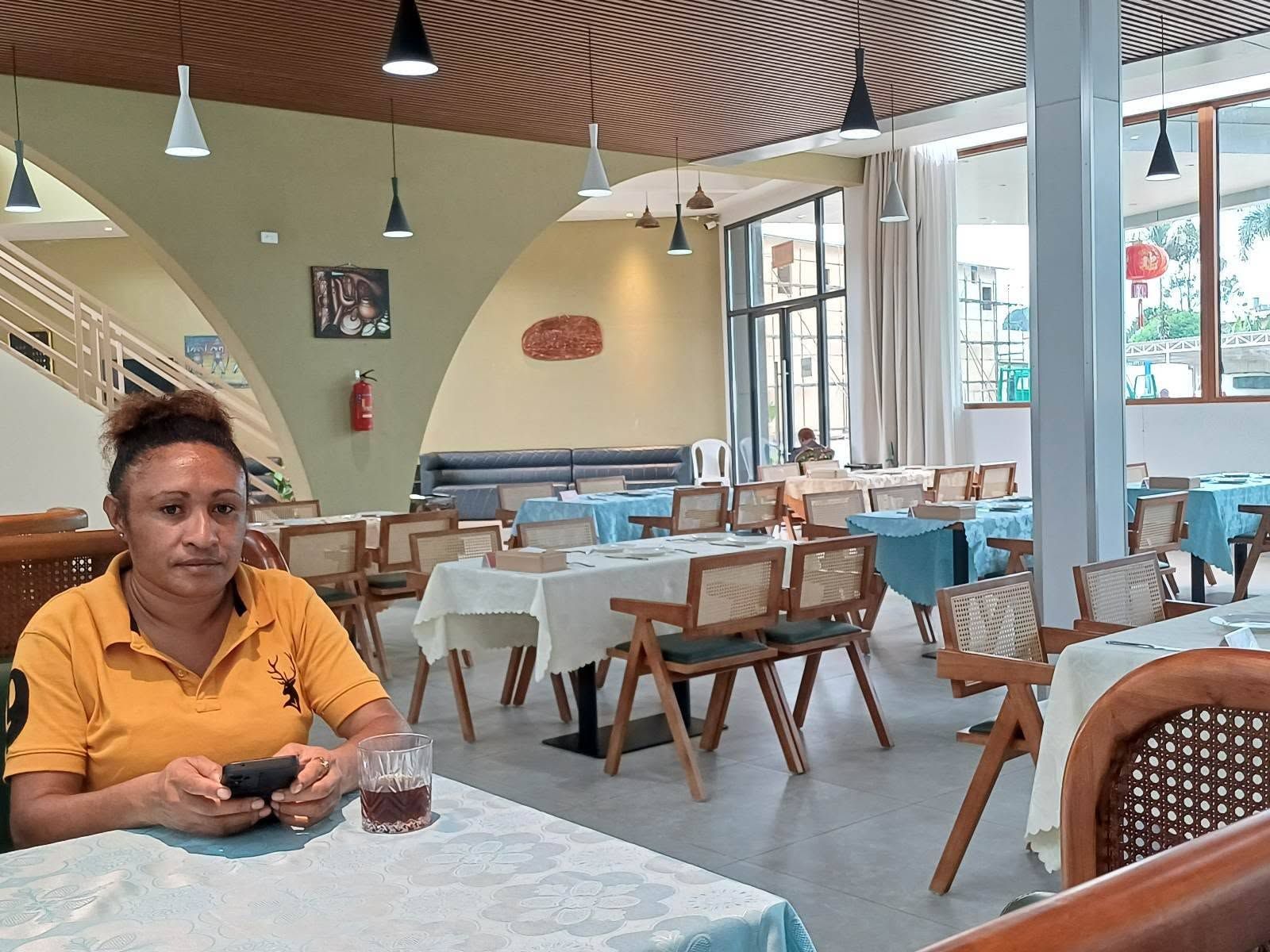 Indoor restaurant dining area with set tables and a person in the foreground.