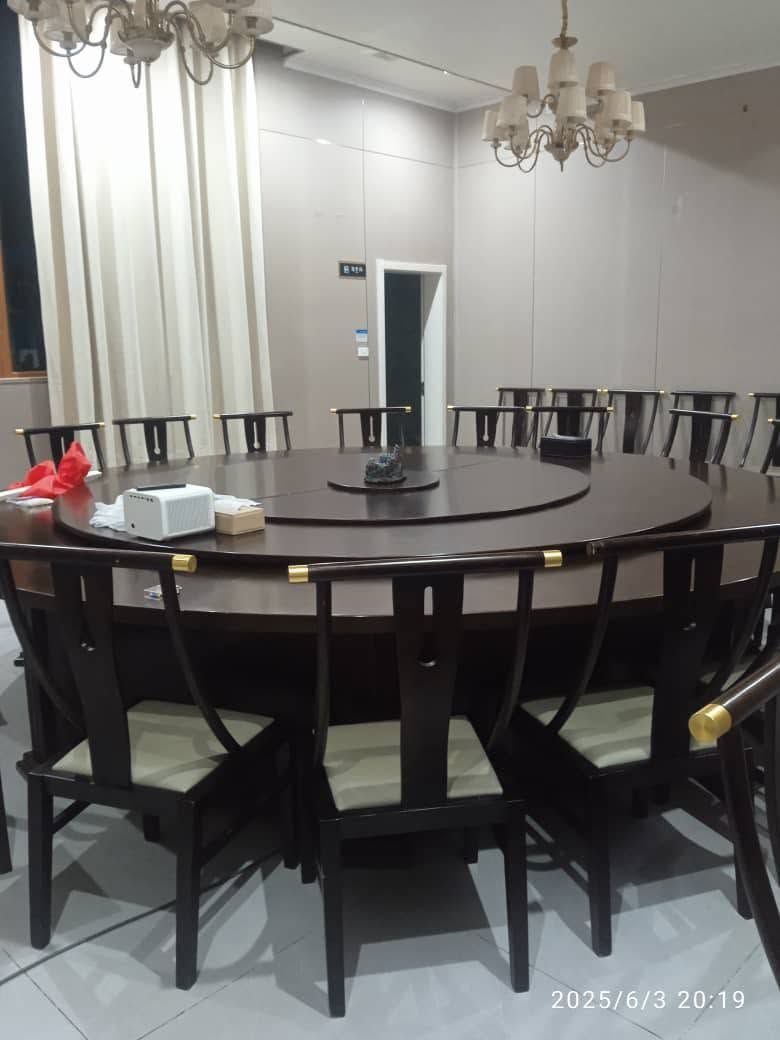 Large circular formal dining table with rotating server and wooden chairs.