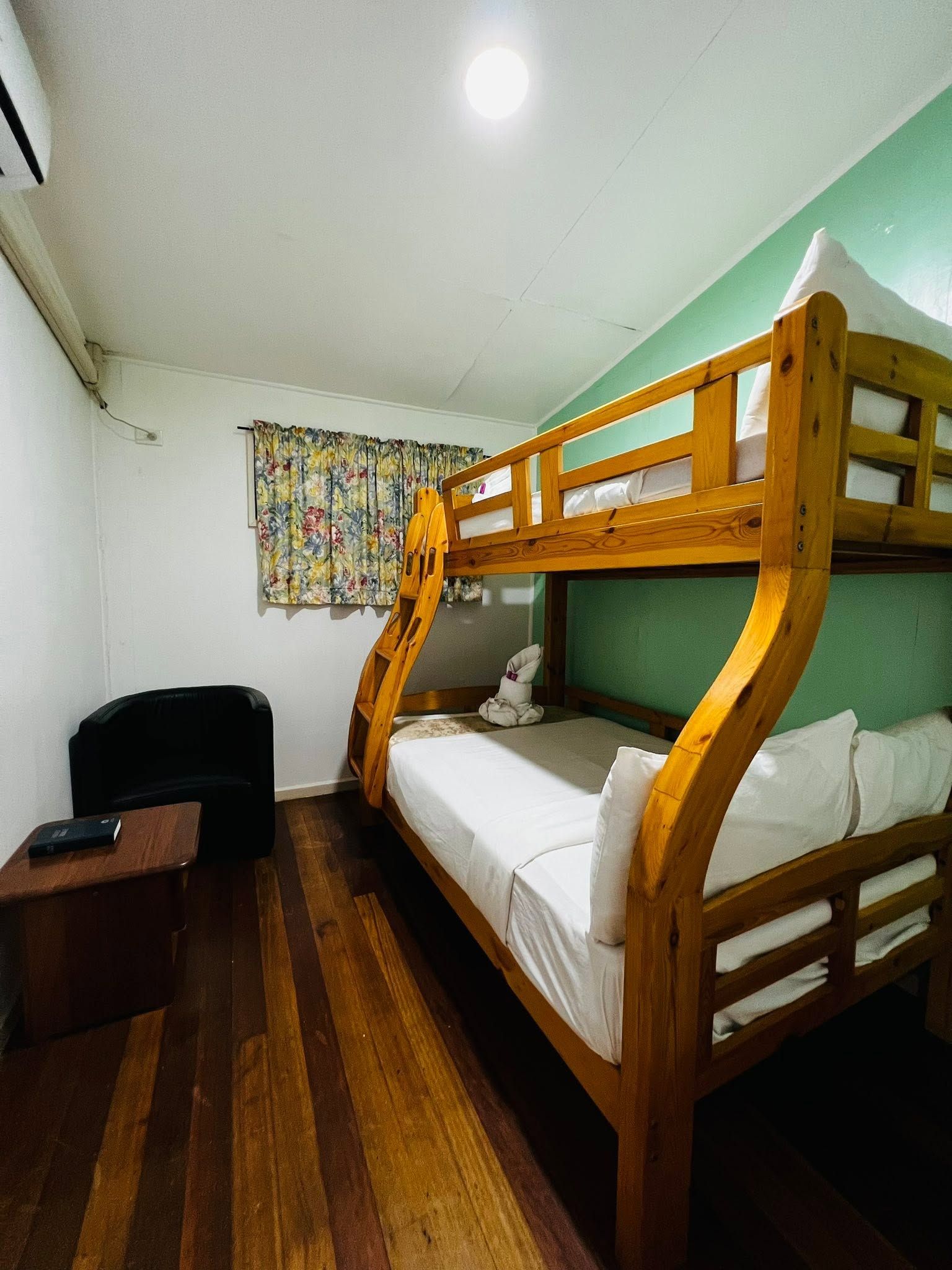 Solid wood bunk beds in a guest room with mint green walls and hardwood floors.