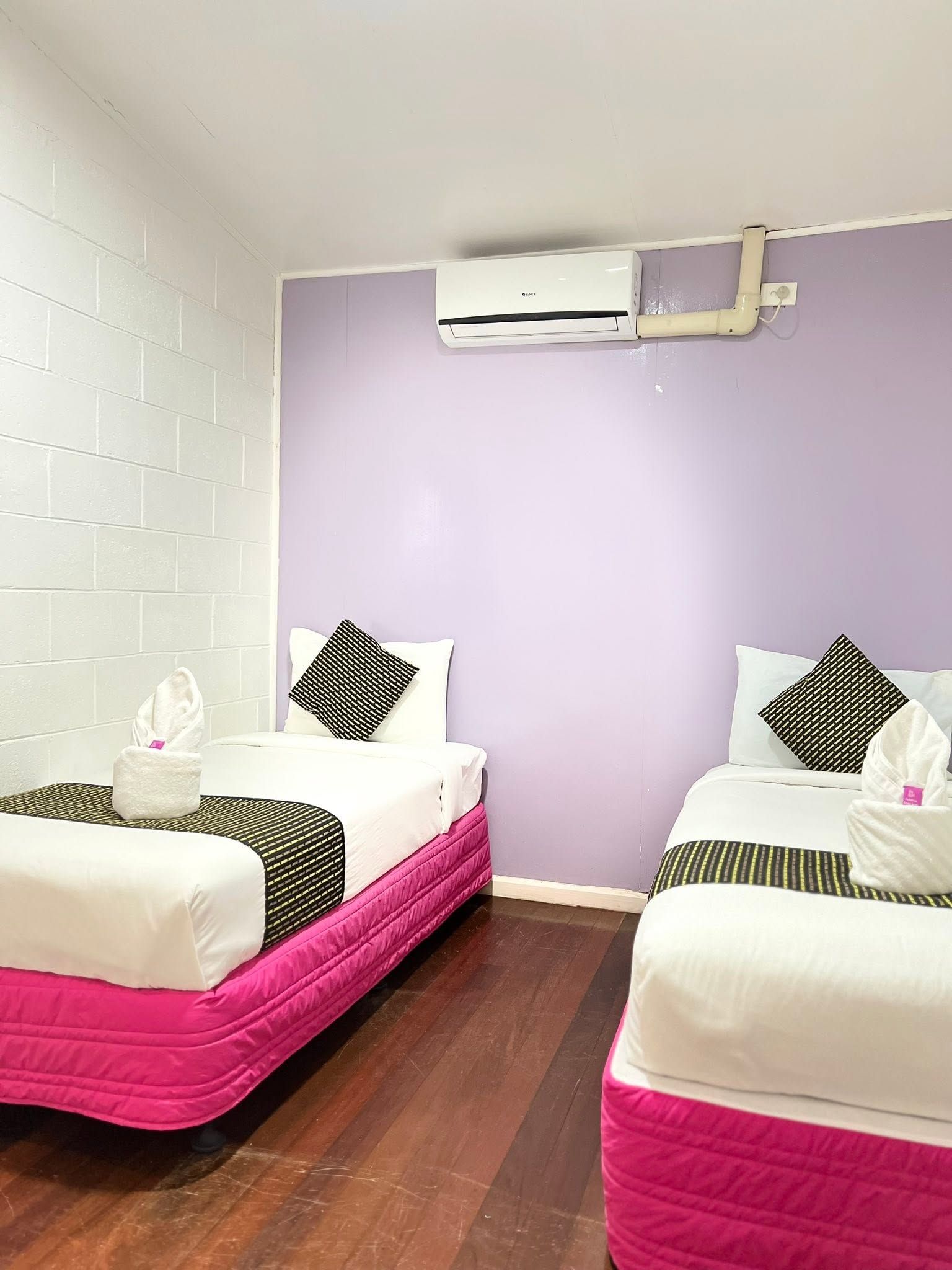 Bright twin room with pink bed bases and individual air conditioning units.