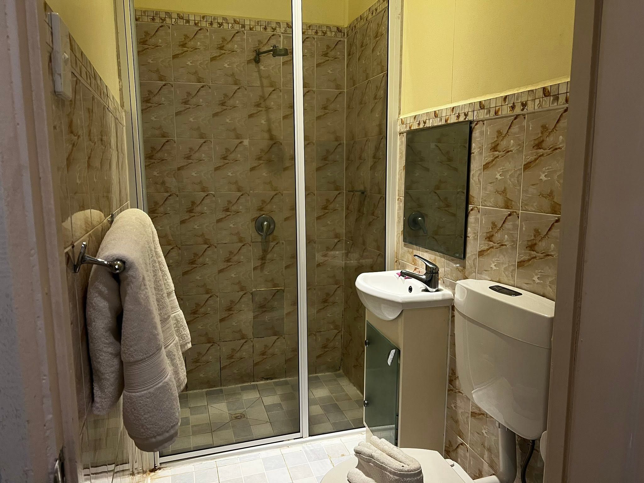 Ensuite bathroom with tiled shower stall, pedestal sink, and white toilet suite.