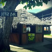 Small thatched beach bar hut with visible signage and SP logo.