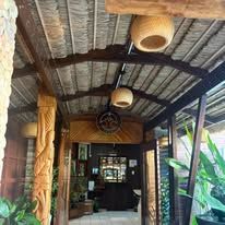 Wooden entrance corridor featuring intricately carved columns and natural ceiling materials.