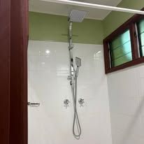 White tiled walk-in shower area with modern chrome rainfall shower head.