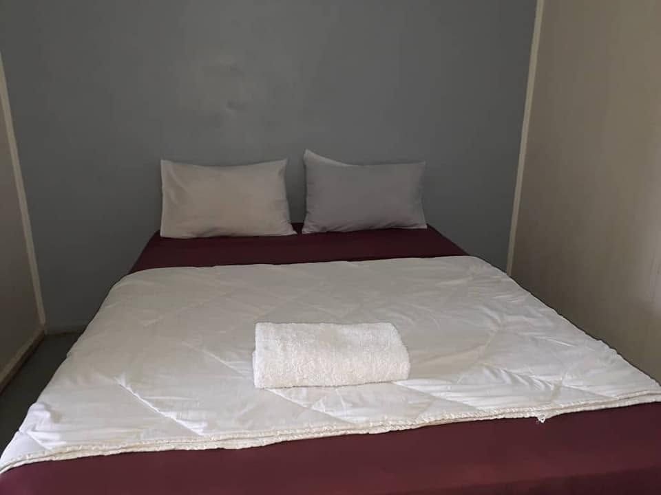 Double bed with white linens and a folded towel in a guest room.