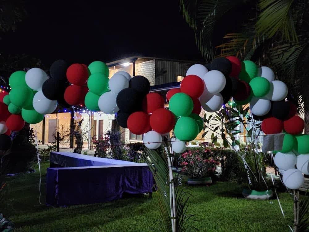 Outdoor event space decorated with colorful balloon arches at night.