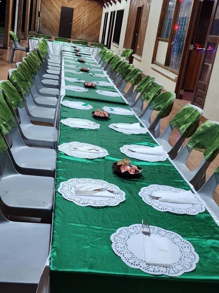 Long banquet table featuring green linens and formal place settings.