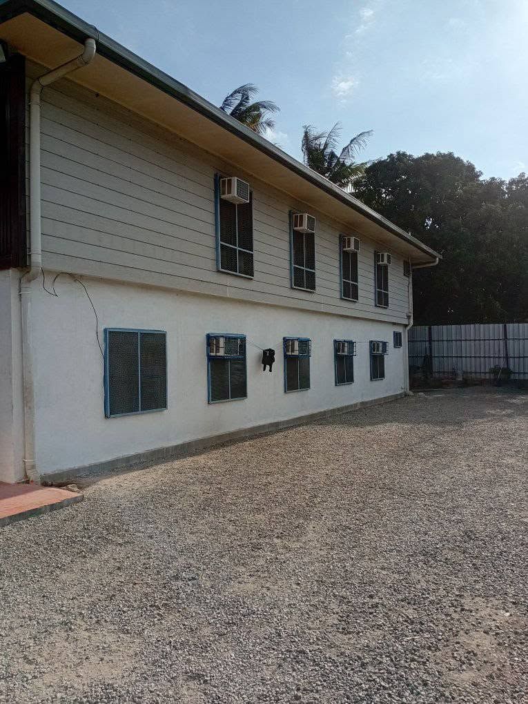 A two-story building featuring multiple air conditioning units on a gravel lot.